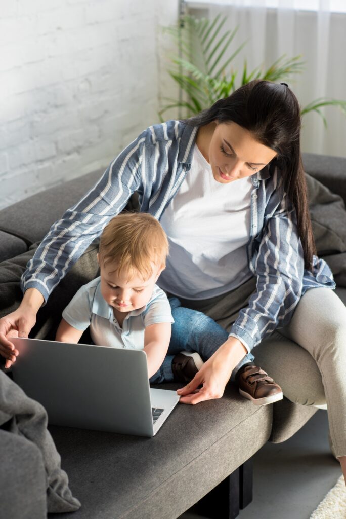mother with laptop and cute baby on sofa at home, work and life balance concept