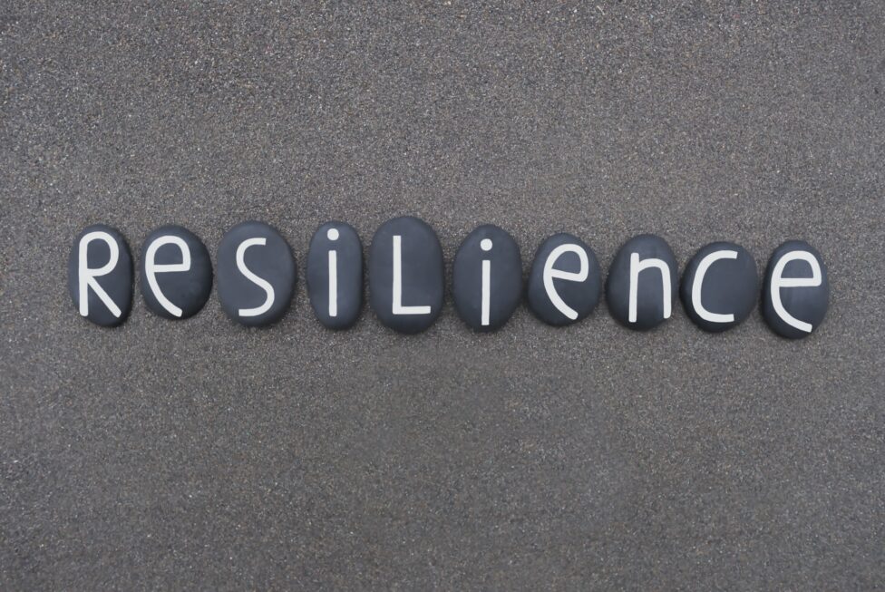 Resilience word composed with black colored stone letters over black volcanic sand