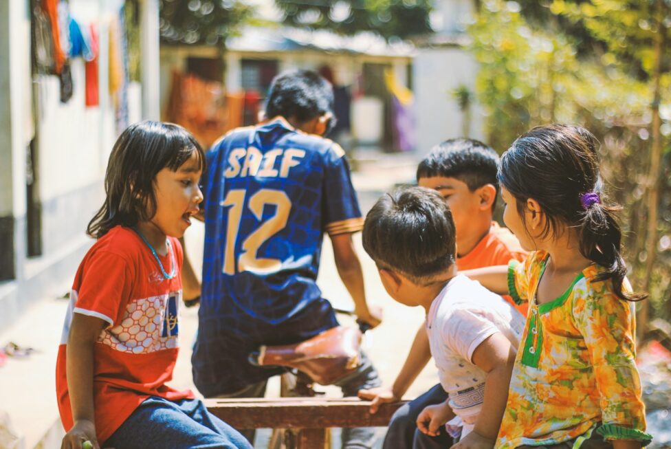 a group of children sitting around a wooden table